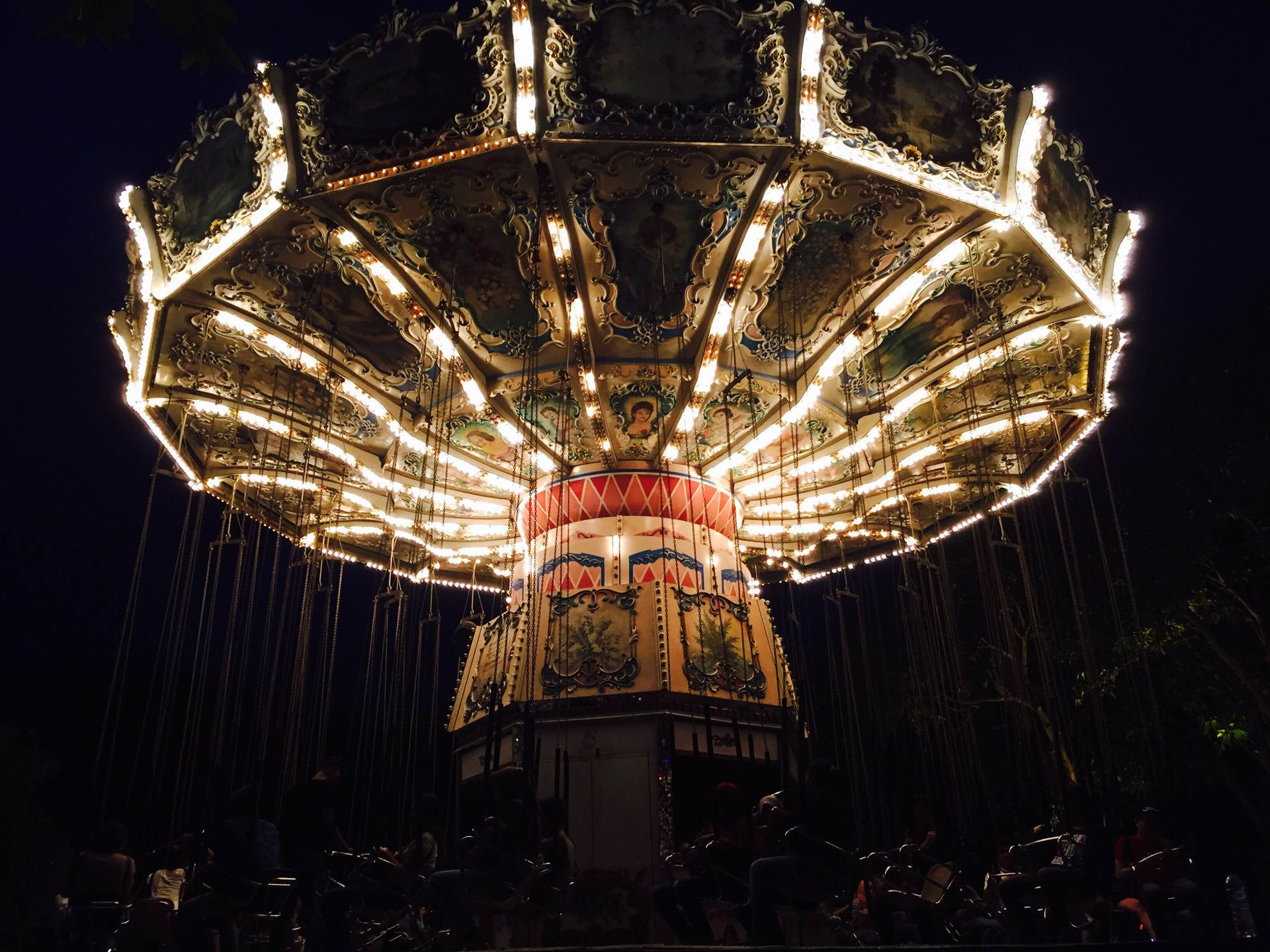 Vibrant night scene of an illuminated carousel in a Jakarta theme park, capturing festive ambiance.