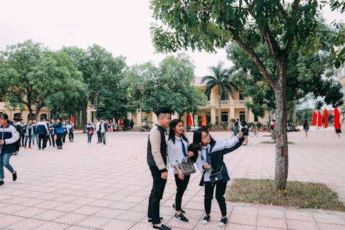 Photo of Two Women Beside Man Taking a Picture