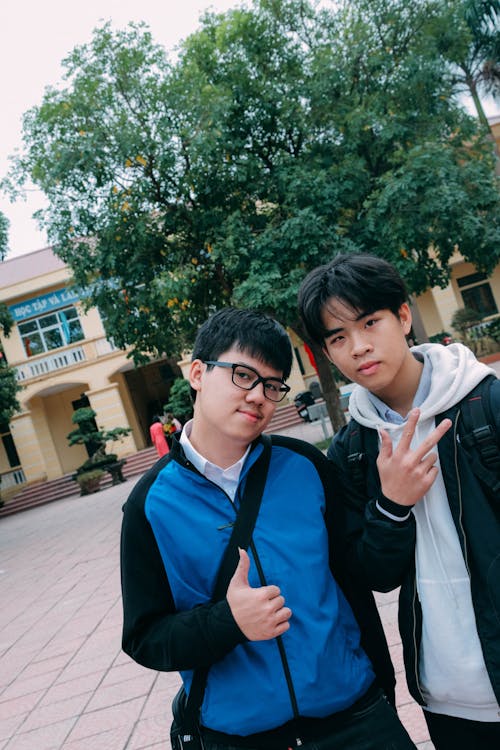 Man in Blue Hoodie Beside a Man in Black Jacket Standing Outdoors Under Blue and White Sunny Sky during Dayimte