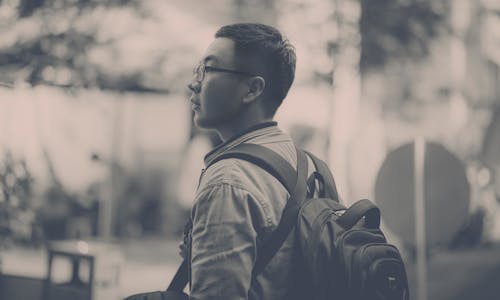 Grayscale Photo of Man Wearing Backpack