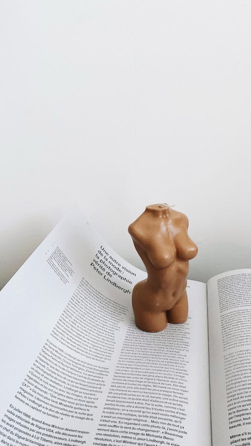 Free From above of creative candle with shape of woman body placed on page of opened book at home Stock Photo