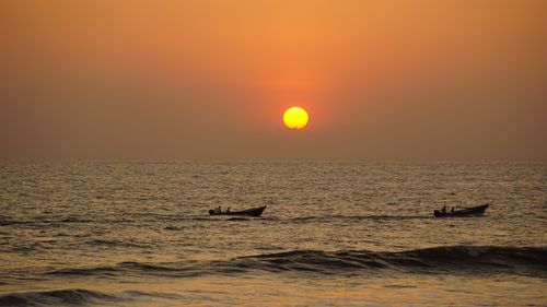 Free Serene ocean sunset with small boats on the horizon, capturing tranquility. Stock Photo