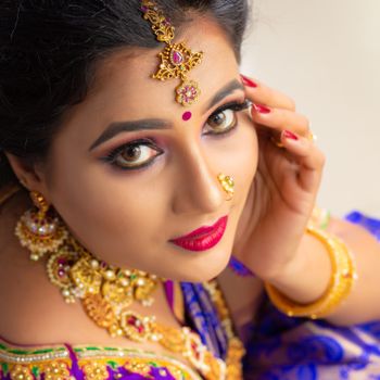 Close-up portrait of an Indian woman adorned with traditional jewelry and makeup, showcasing cultural elegance.