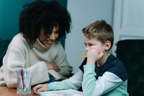 Free A mother and son share a joyful moment while doing creative activities indoors. Warm and homey atmosphere. Stock Photo