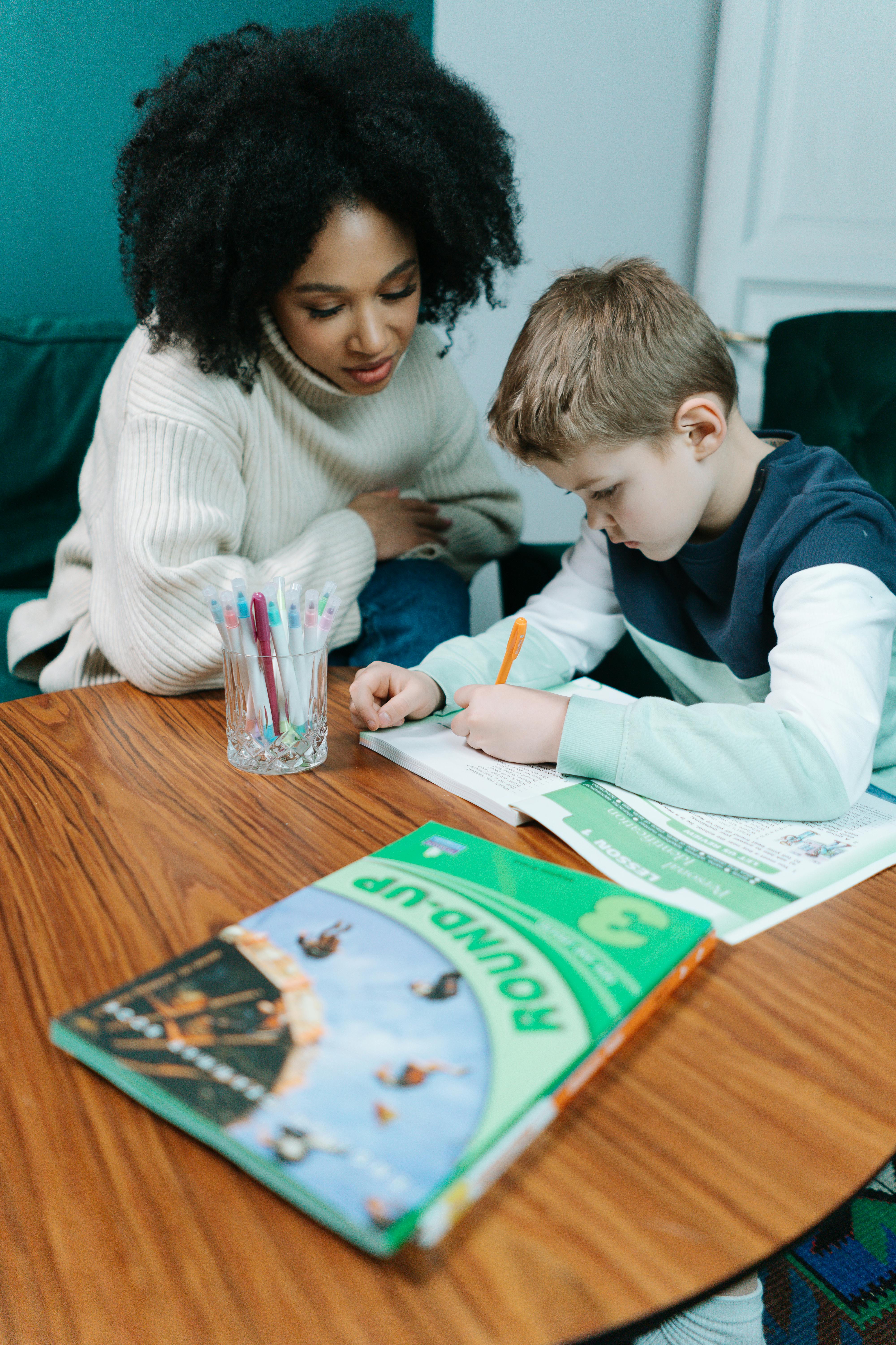 woman and boy writing in book