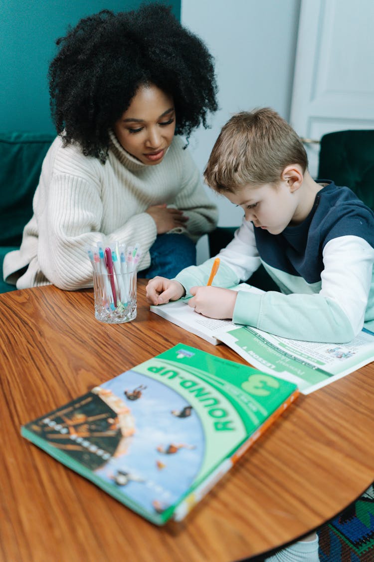 Woman And Boy Writing In Book