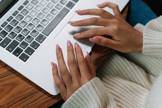 A close-up view of hands typing on a laptop keyboard, showing a cozy and productive workspace.