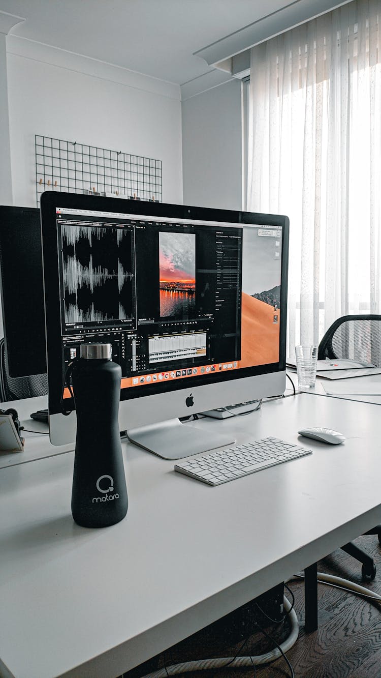 Computer Monitor With Keyboard On Desk Near Water Bottle