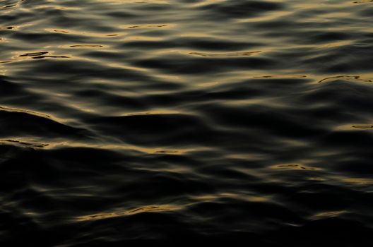 Calm ocean water with gentle ripples reflecting the sunset light.