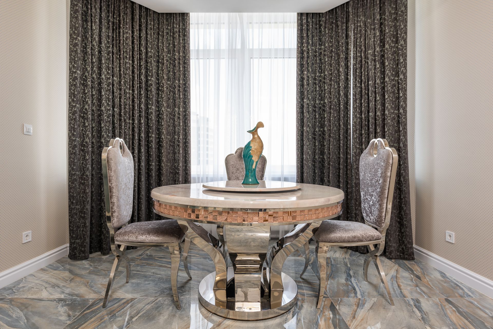 A stylish modern dining room featuring a round table, two chairs, and a decorative bird sculpture.