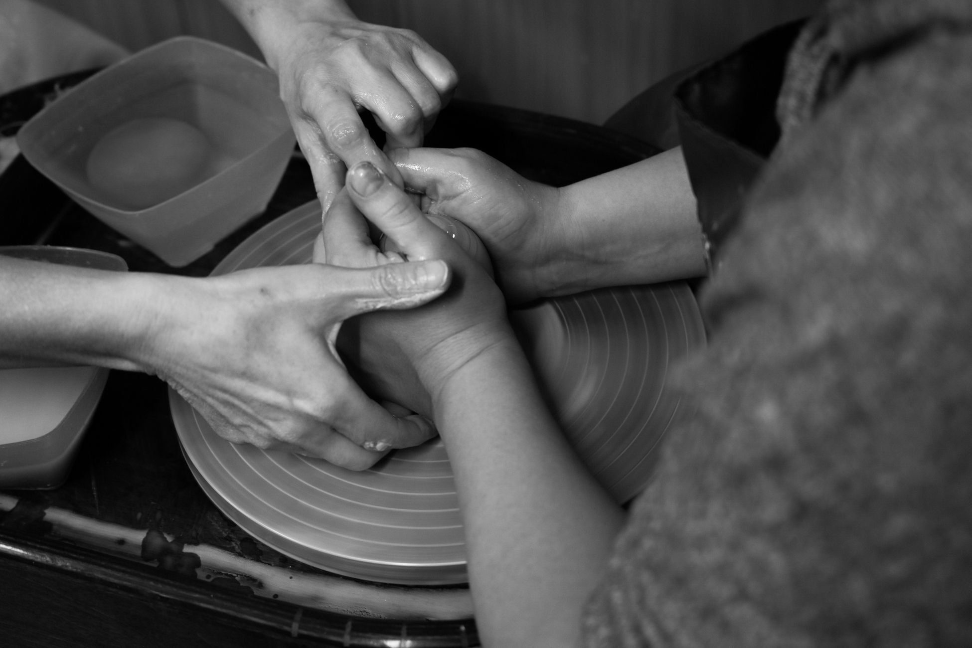 Close-up of hands working on pottery wheel, showcasing the art of sculpting in black and white.