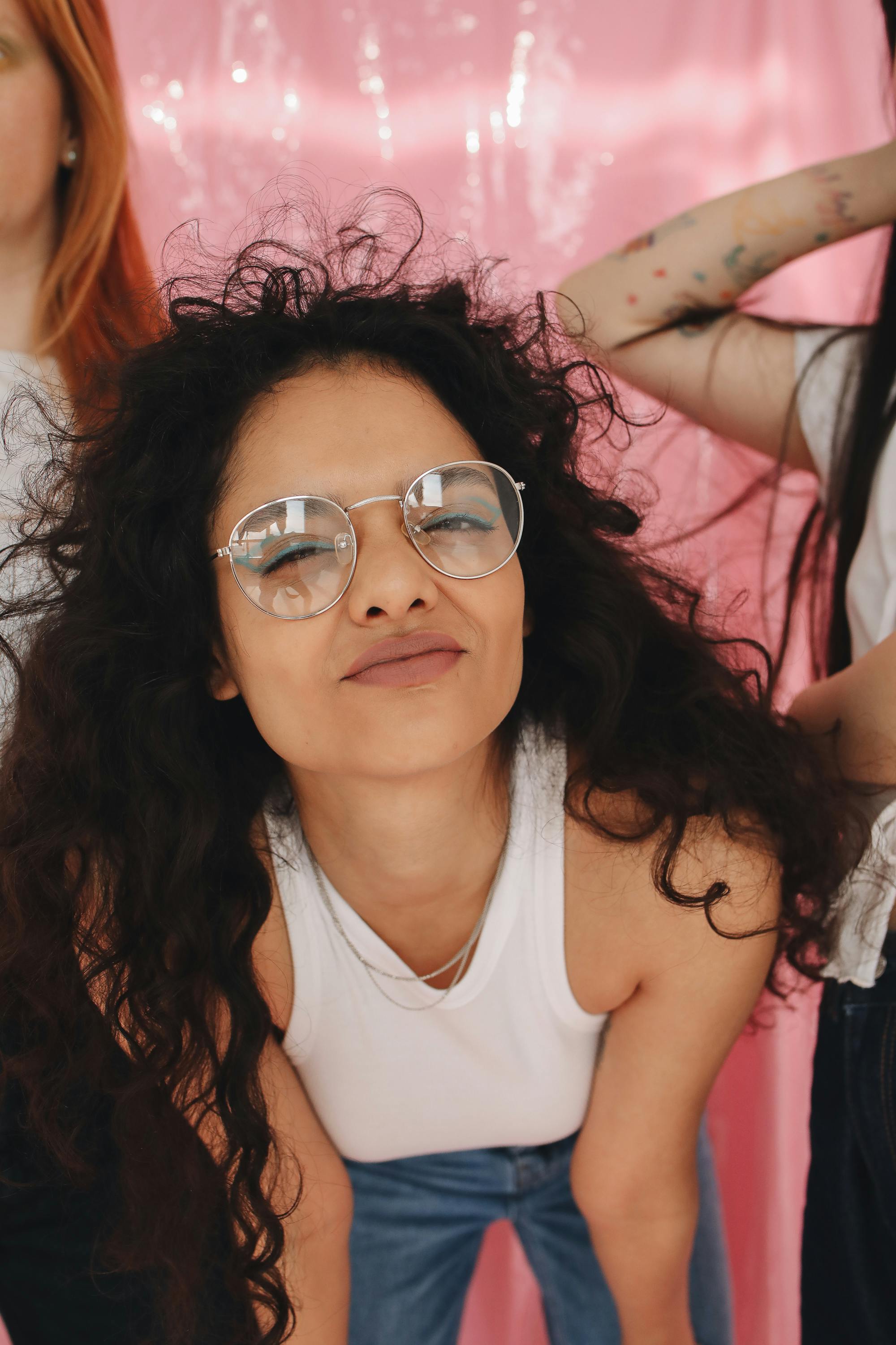 a girl in white tank top smiling while wearing eyeglasses