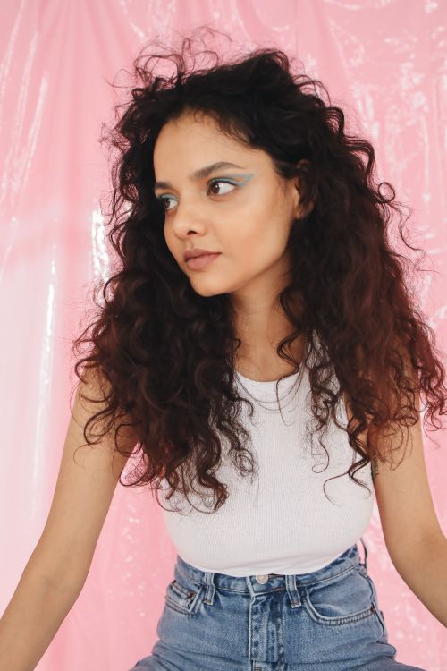 Free Stylish young woman in a studio with pink backdrop and eye-catching makeup. Stock Photo