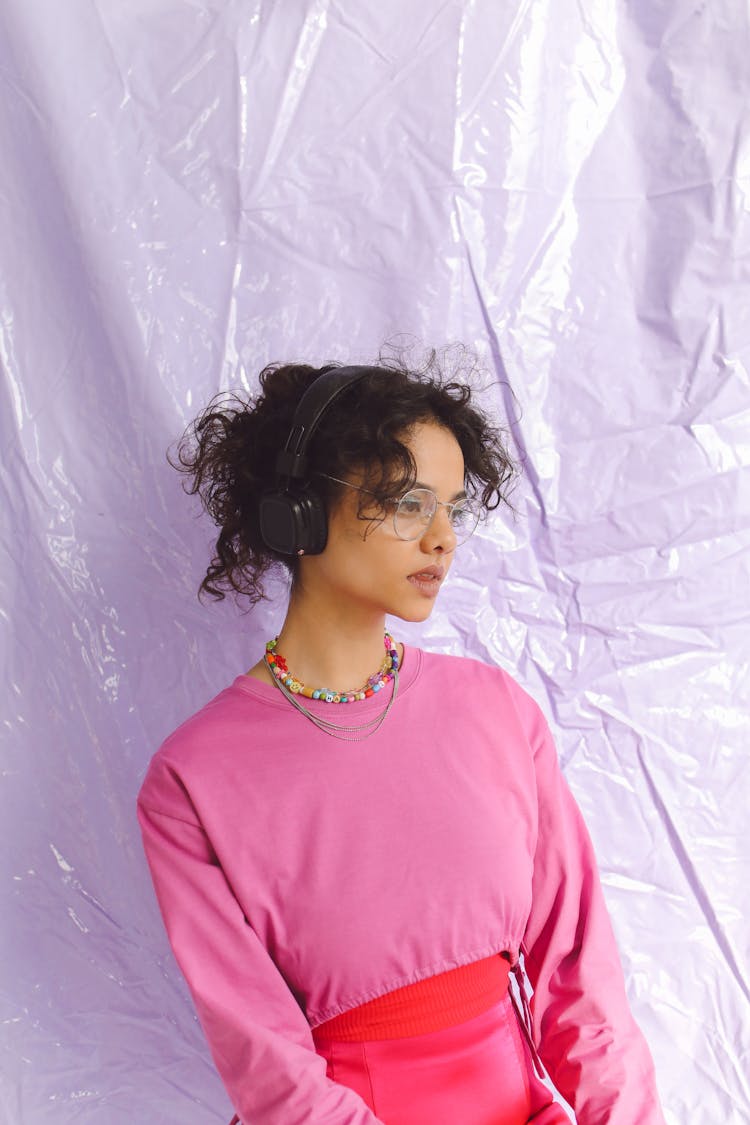 Woman In Pink Long Sleeves Wearing Headphones While Looking Afar