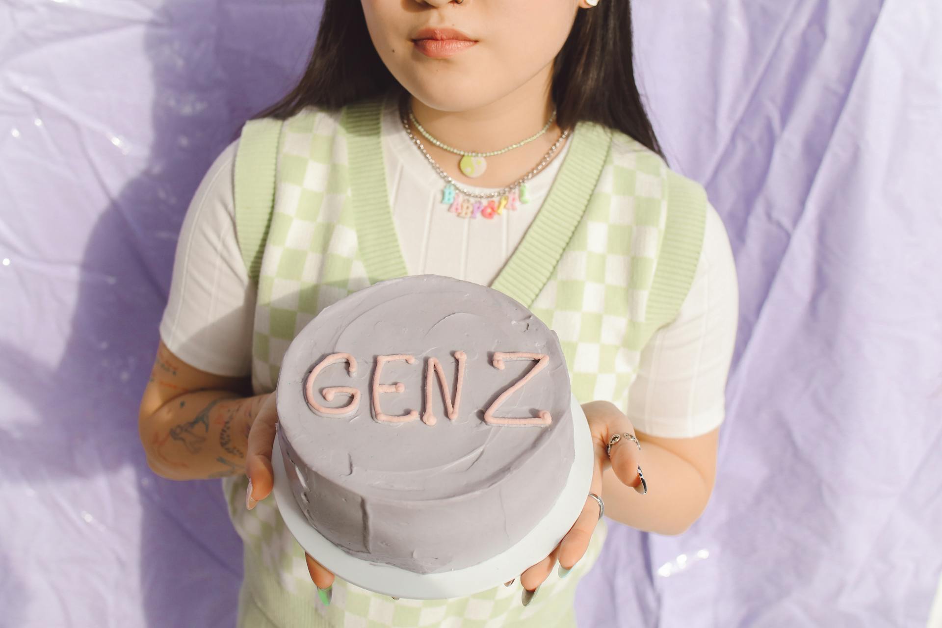 Close-up of a young woman holding a Gen Z themed cake, showcasing modern youth culture.