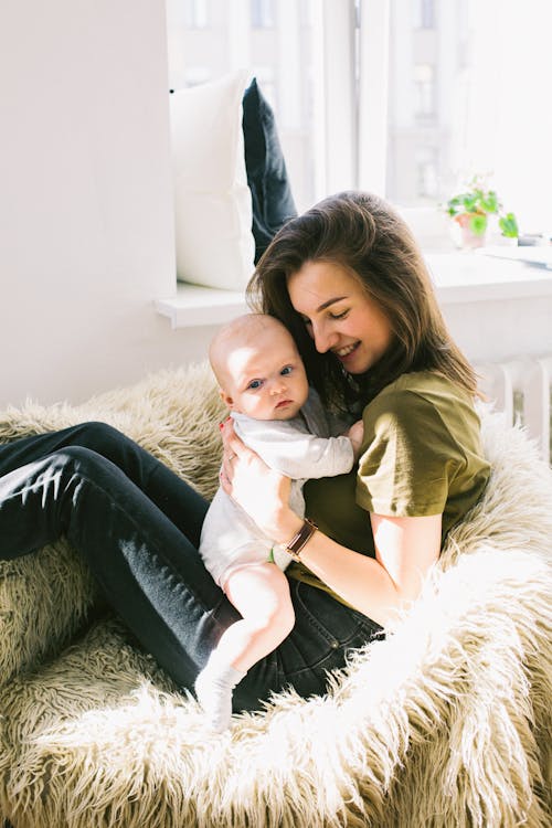 Woman in Green Shirt Holding Baby While Sitting