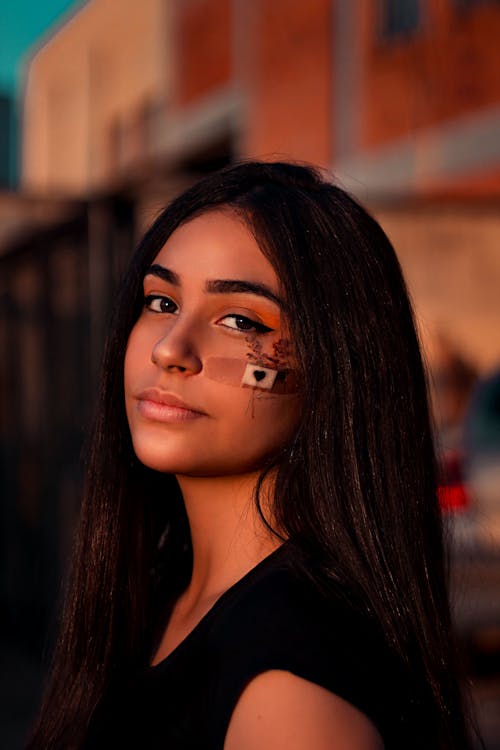 Beautiful Woman with a Band-Aid on Her Cheek Looking at the Camera