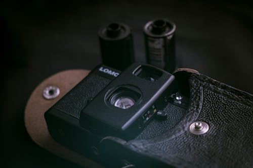 An Analog Camera Inside a Black Case on a Black Surface