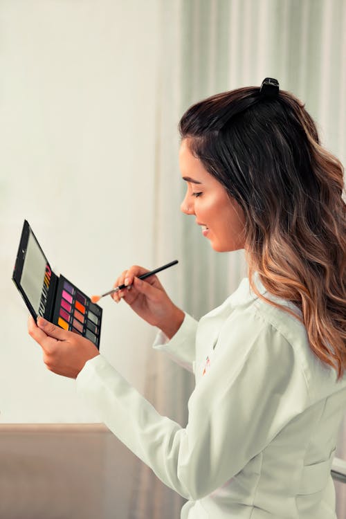 A Woman Looking at the Eyeshadow Palette she is Holding