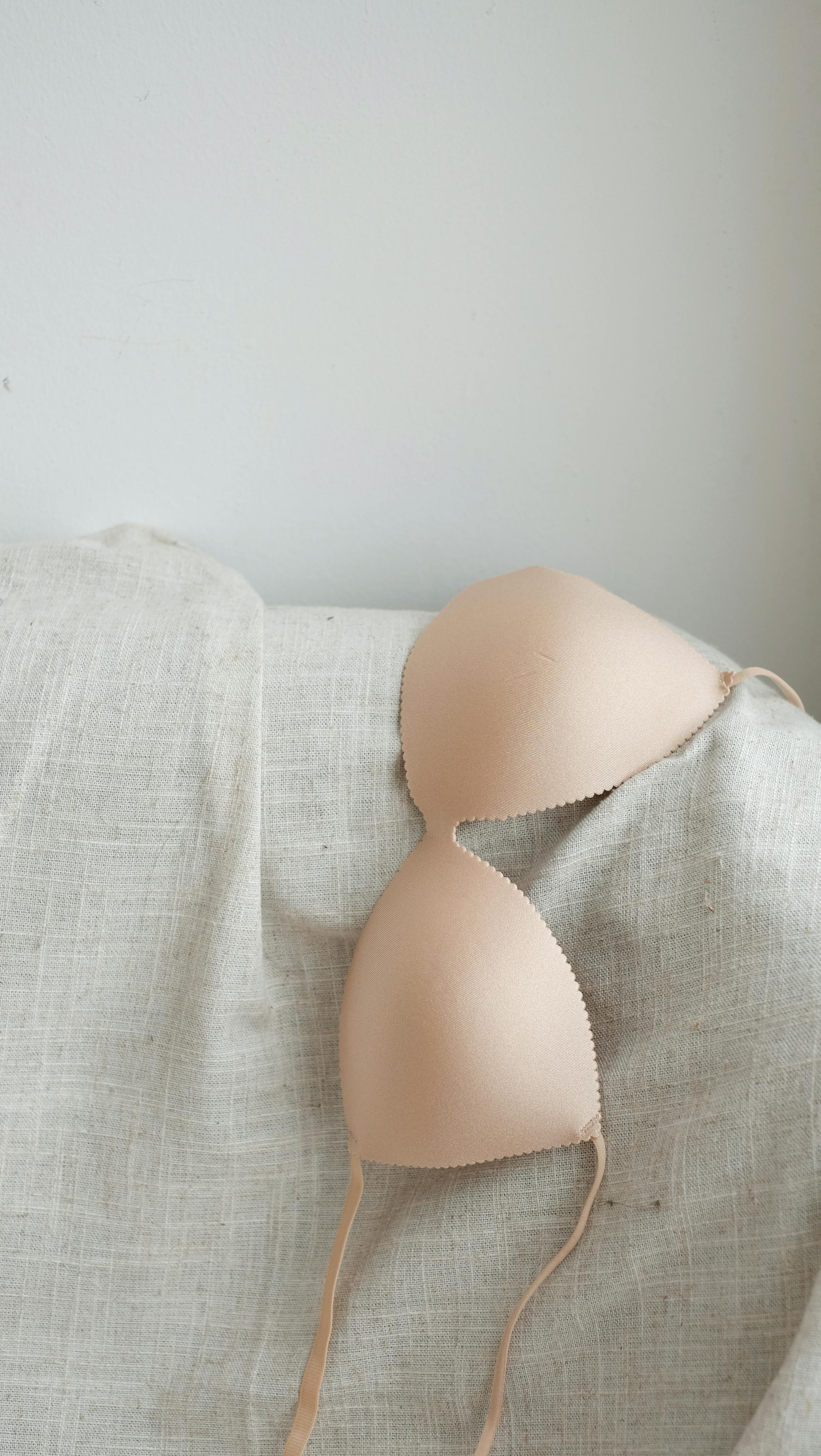Minimalist beige bra displayed on neutral fabric background, showcasing simple elegance.