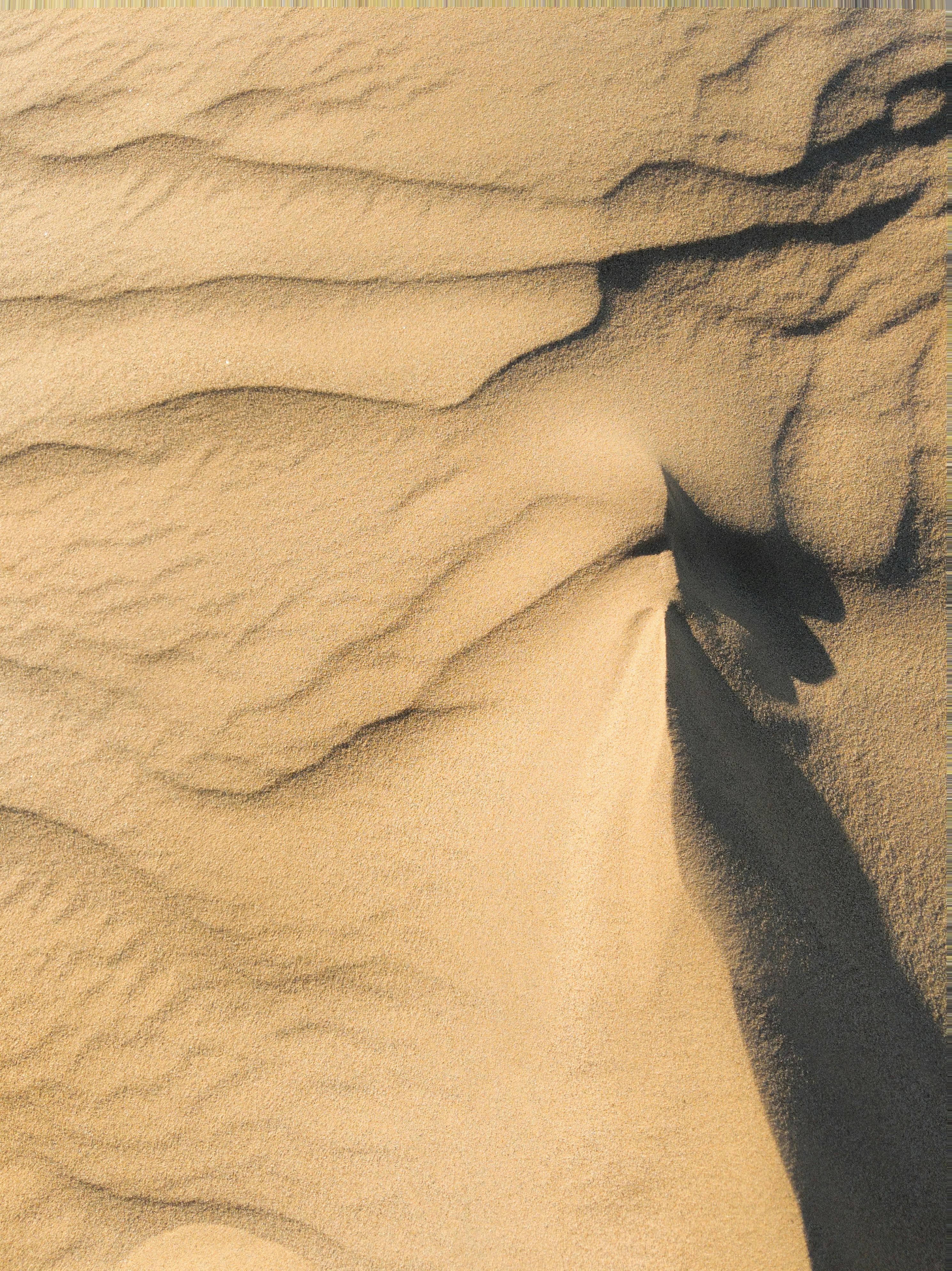 Aerial view of textured sand dunes with abstract patterns in California desert.