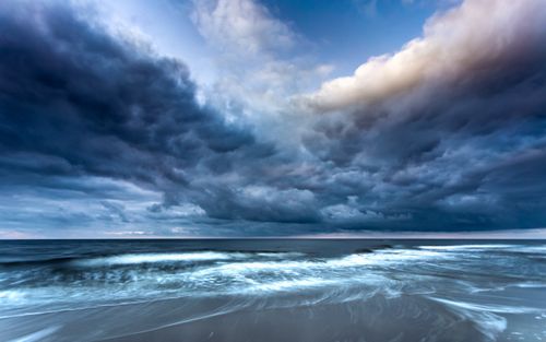 Free Majestic dark clouds over tranquil ocean waves create a serene yet dramatic scene. Stock Photo
