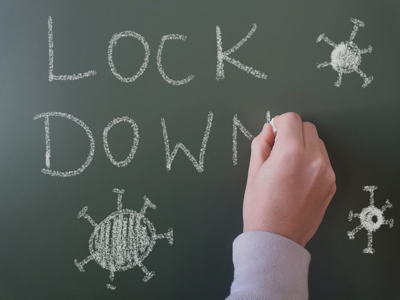 hand drawing the word lockdown on chalkboard with chalk symbolizing pa