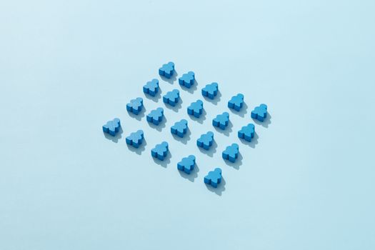 A flat lay of neatly arranged blue meeples on a light blue background, perfect for board game enthusiasts.