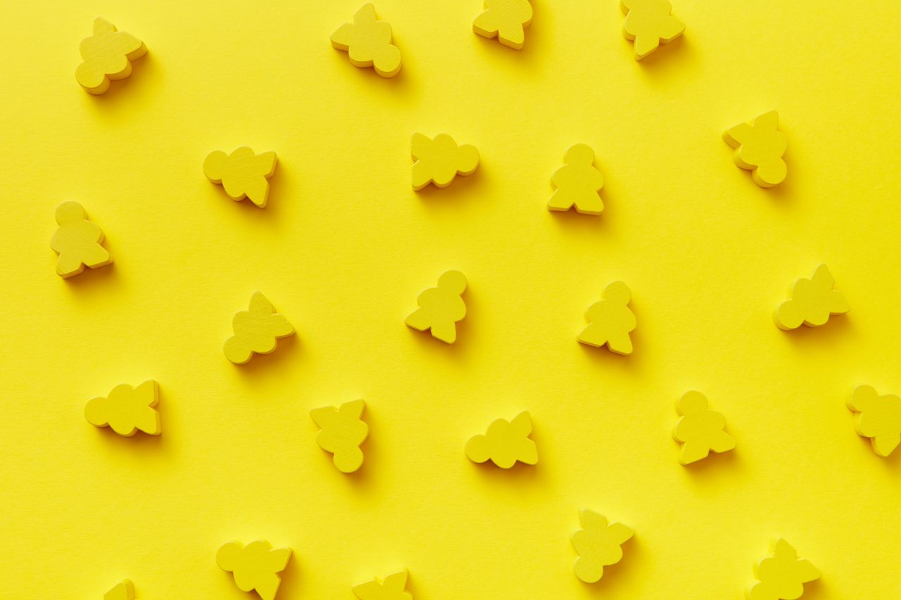 bright yellow abstract pattern with toy meeples against a yellow backg