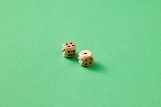 Close-up of two wooden dice on a vibrant green background.