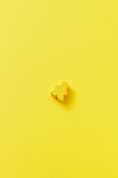 A single yellow meeple on a bright yellow background, showcasing minimalist design.