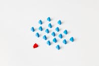 Photo of a Red Meeple Near Blue Meeple Pieces