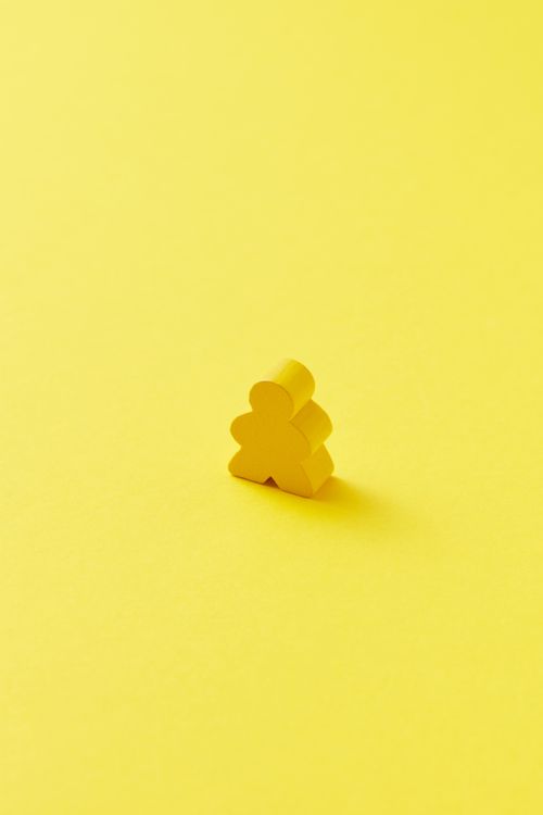 Free Minimalist photo of a yellow meeple on a bright yellow backdrop, offering abundant copyspace. Stock Photo