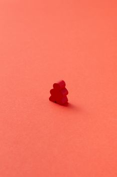 A single red meeple standing on a solid red background offering copy space.