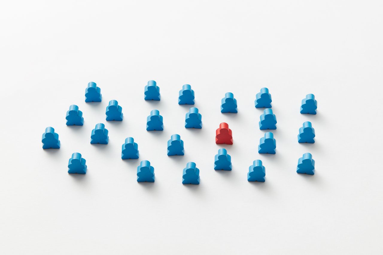 a red meeple stands out in a pattern of blue figures symbolizing indiv