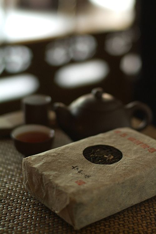 Free Close-up view of a traditional tea setup with a rustic teapot, cups, and loose leaf tea packet. Stock Photo