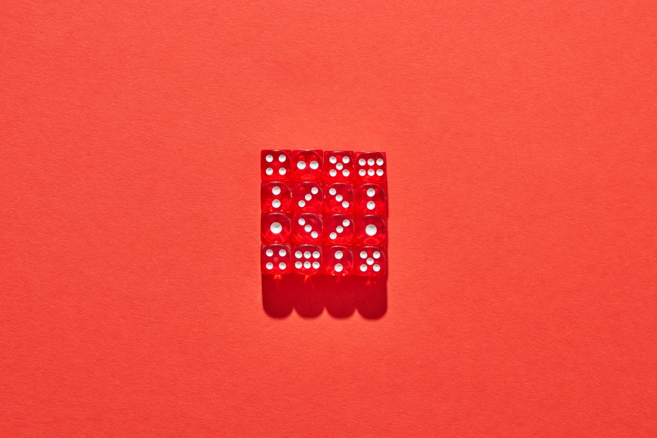 red translucent dice neatly arranged on a matching red background cast