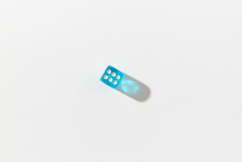 Minimalist photo of a blue dice set against a white background with shadow, creating a stark contrast.