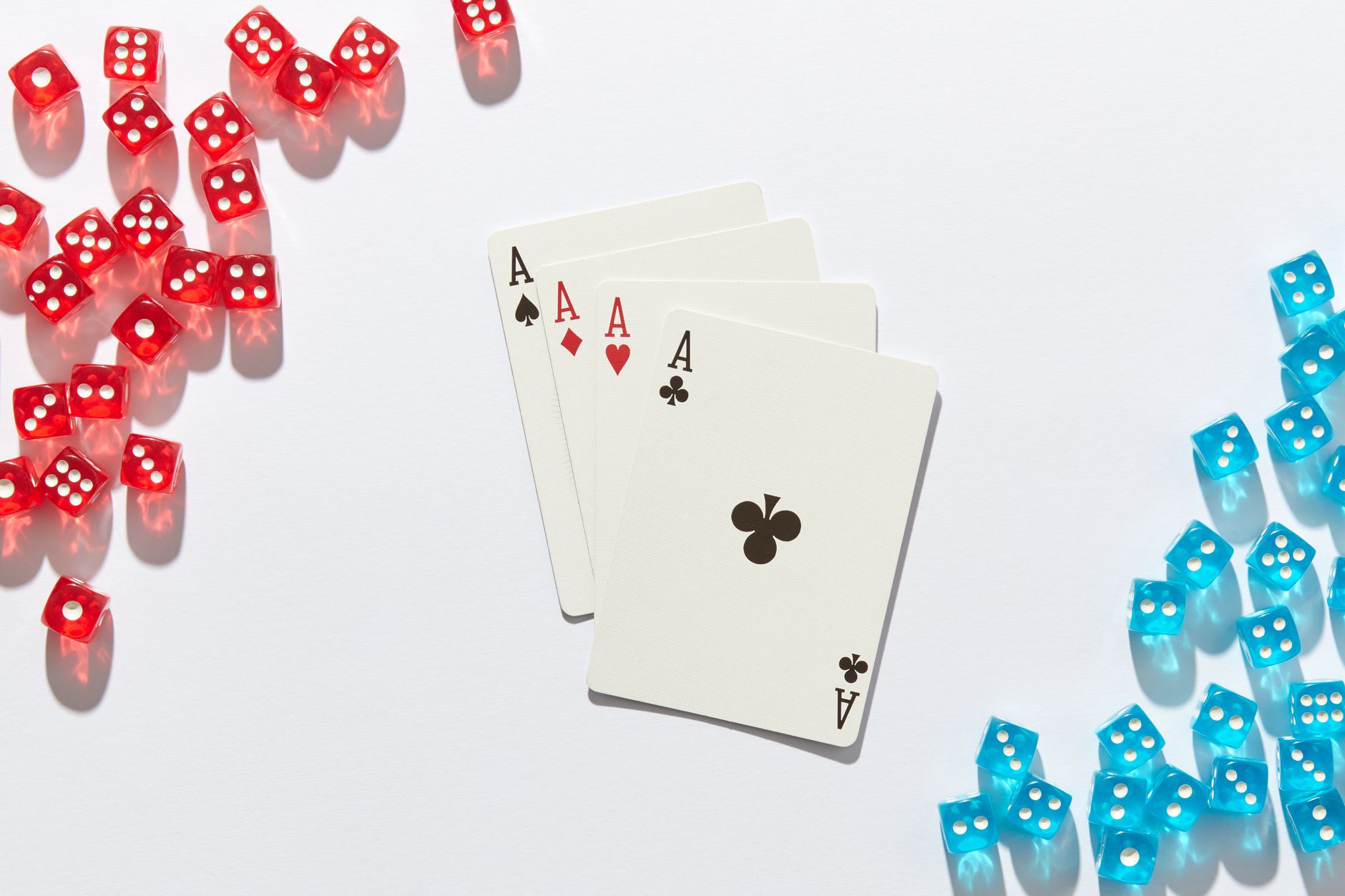 Four aces surrounded by red and blue dice on a white surface, perfect for poker or casino themes.