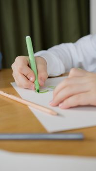Close-up of a child drawing with a green pen, capturing creativity in education.