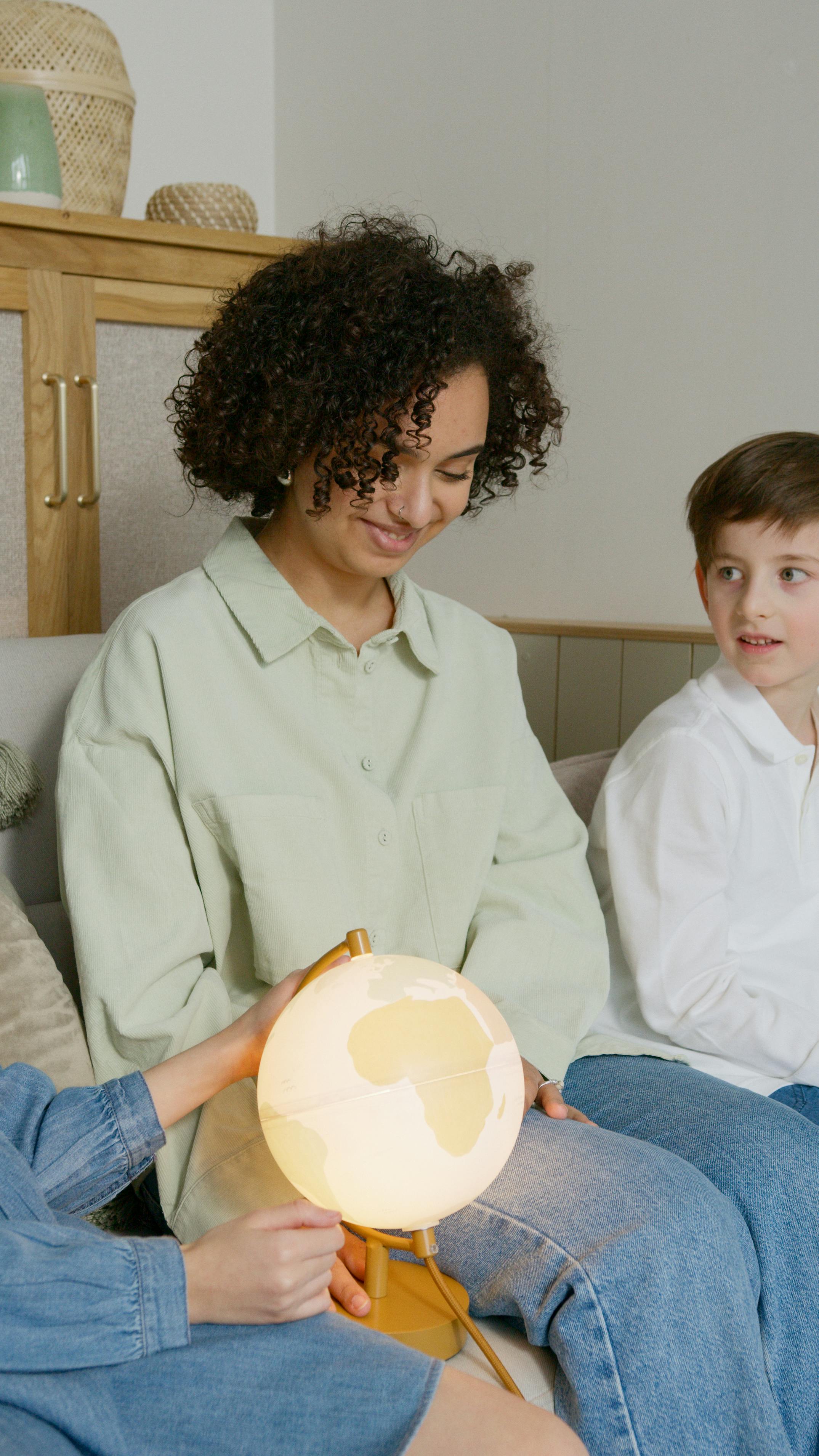 A diverse group engaging with a globe indoors, promoting education through interactive learning.