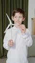 A Boy in a White Long Sleeved Shirt Holding a Model Windmill