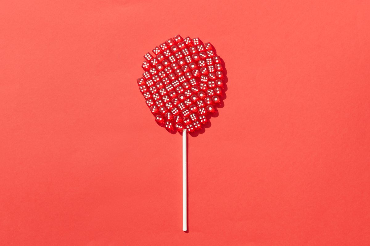 Artistic concept of a lollipop made from red dice against a vivid red backdrop, emphasizing creativity and color contrast.
