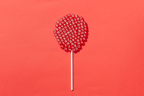 Free Artistic concept of a lollipop made from red dice against a vivid red backdrop, emphasizing creativity and color contrast. Stock Photo