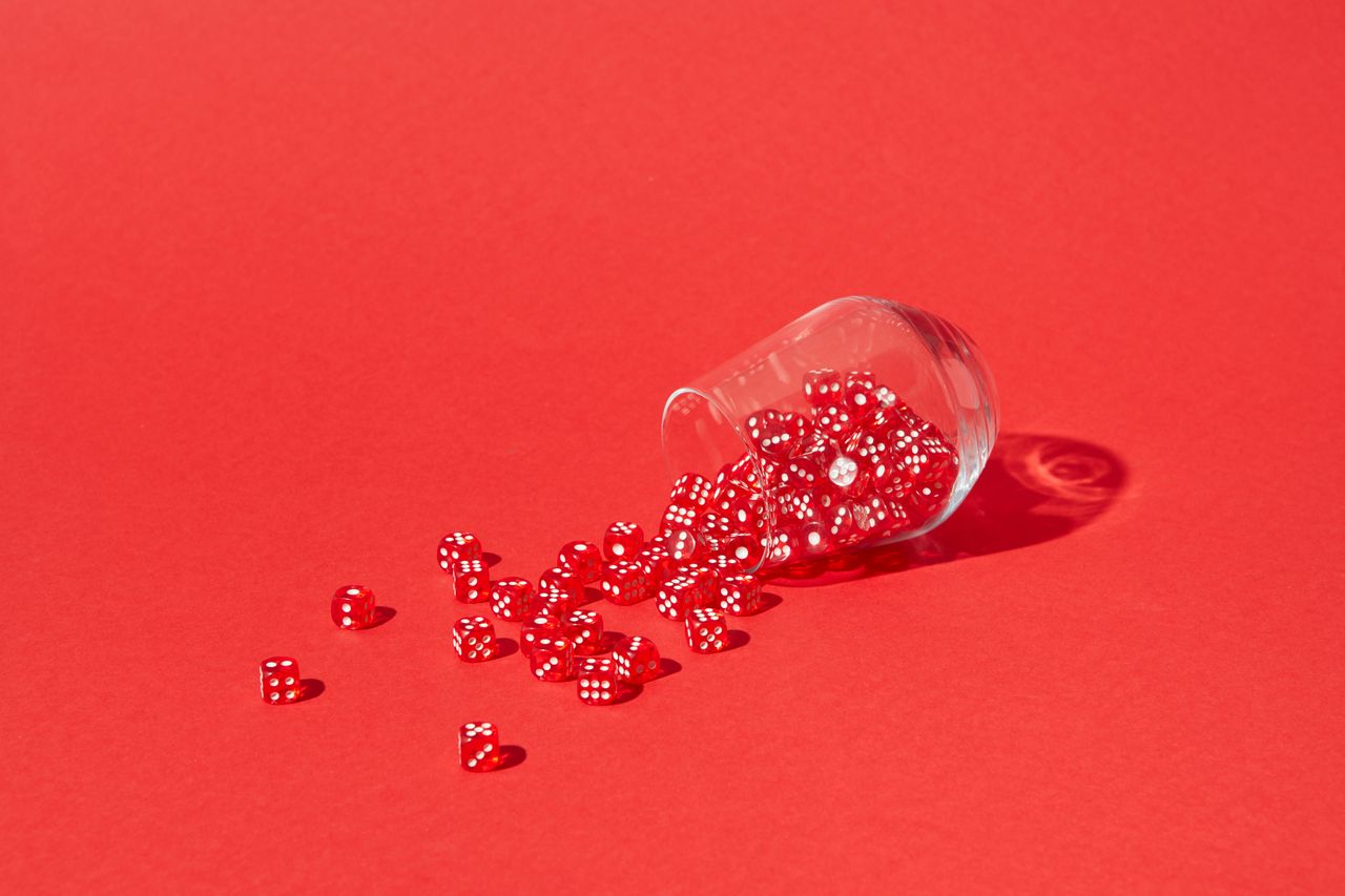red dice spilling from a glass on a bright red background capturing a