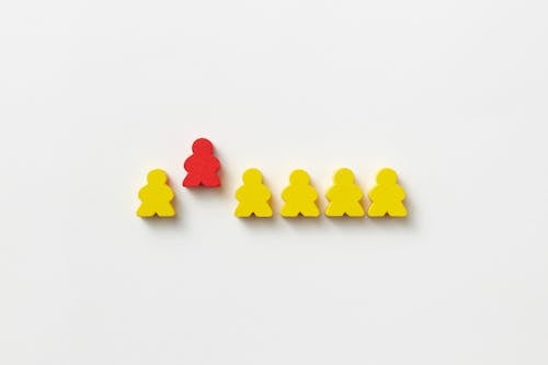 Red and Yellow Human Shape Wooden Blocks On Gray Background