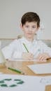 A Boy Looking On A Paper Across The Table