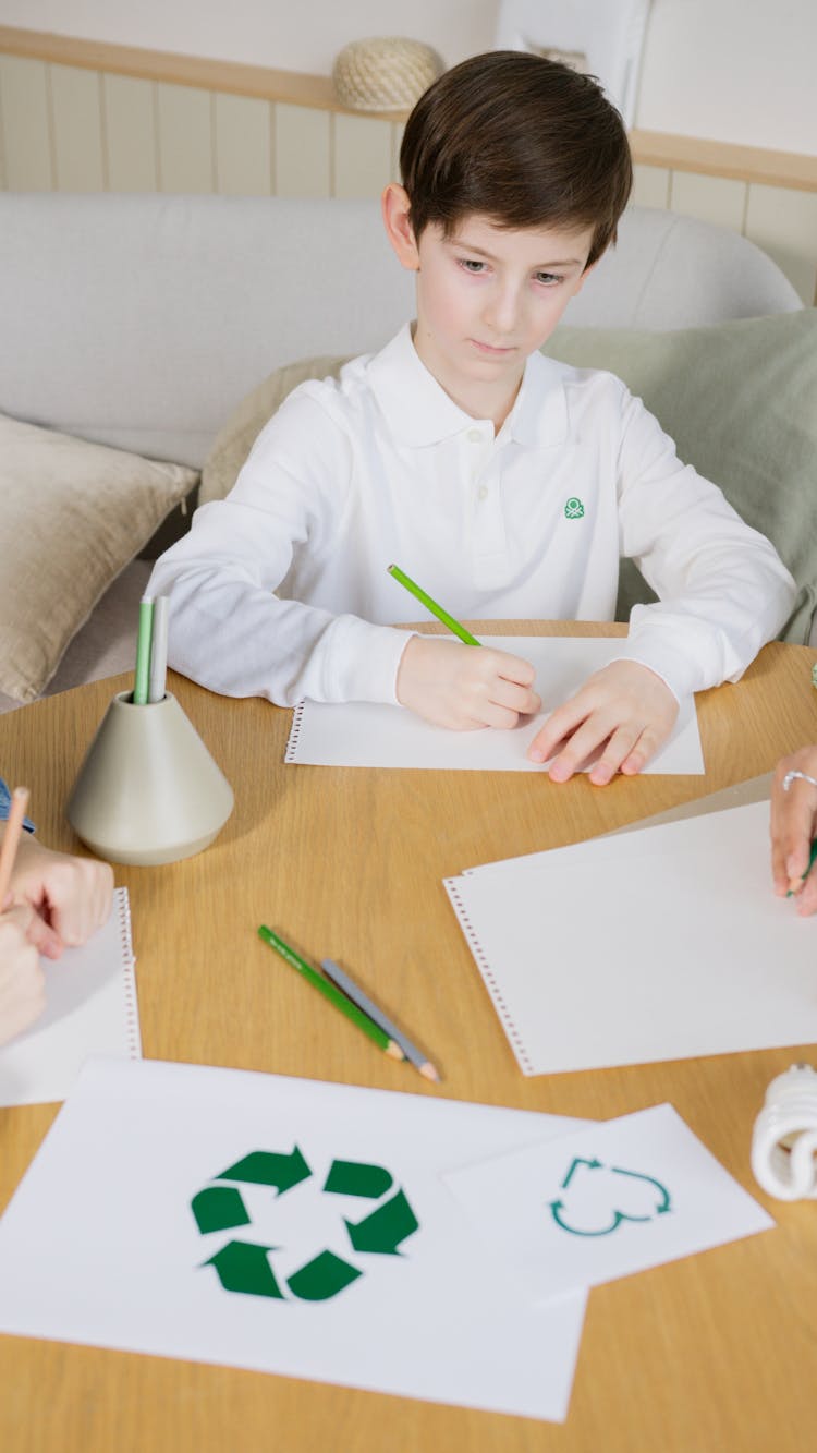 A Young Boy In White Long Sleeves Writing On Paper