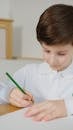 Photograph of a Boy Writing with a Green Pencil