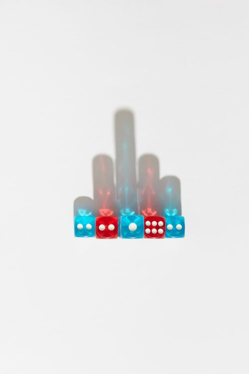 Free Colorful dice arranged on a white background casting artistic shadows, top view. Stock Photo
